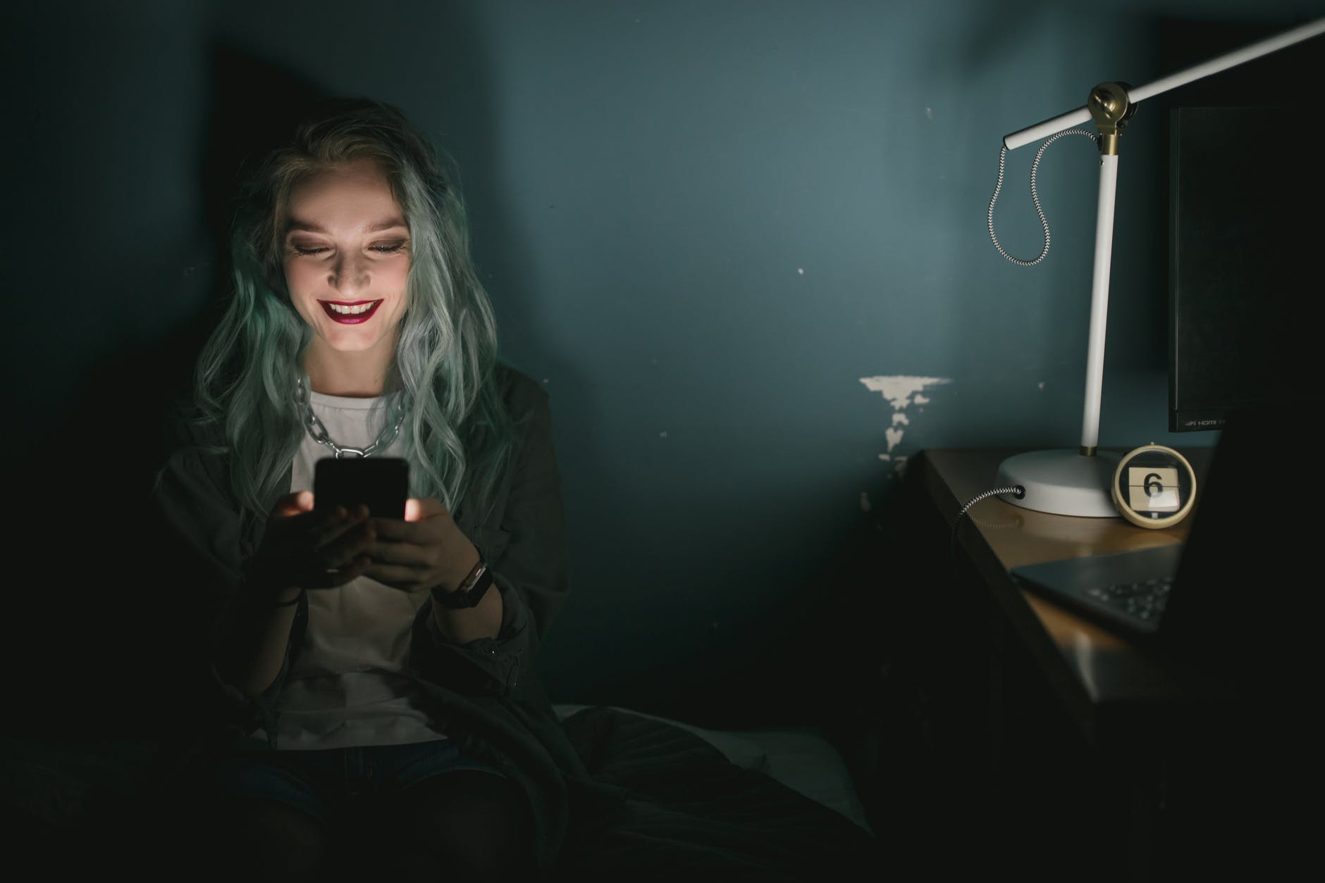 woman in the dark looking at her smartphone smiling